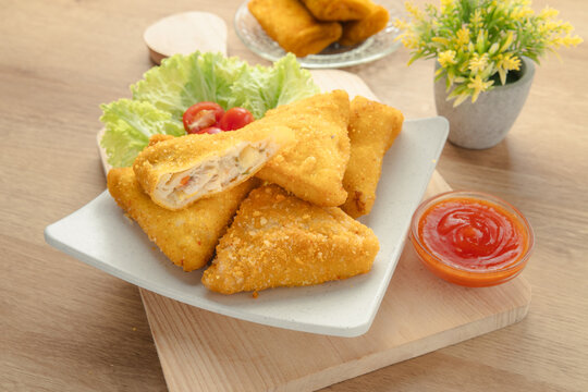 Crispy Triangular Fried Chicken Risoles Ragout with Savory Vegetable Filling Served with Chili Sauce on White Plate