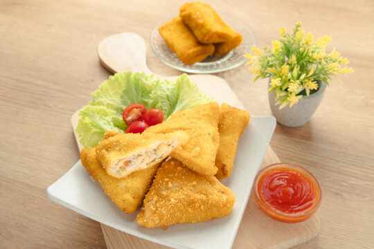 Crispy Triangular Fried Chicken Risoles Ragout with Savory Vegetable Filling Served with Chili Sauce on White Plate