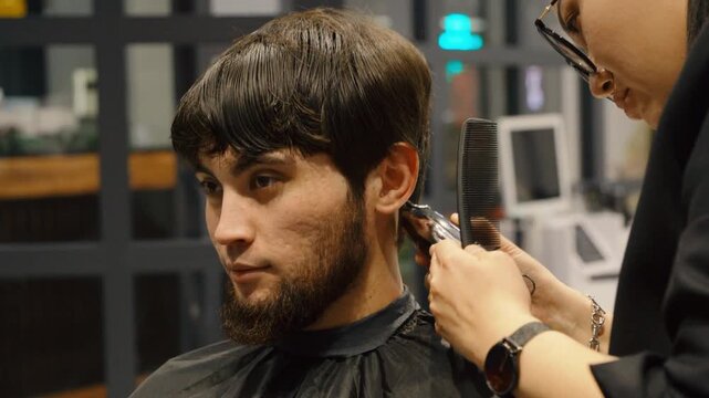 Barber shaping sideburns of a man with electric shaver