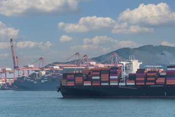 Fototapeta premium A large cargo ship loaded with colorful shipping containers approaches a container terminal in Busan, South Korea. Symbolizing efficiency in global maritime commerce. 
