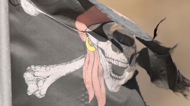 Close Up of Tattered Jolly Roger Pirate Flag Waving in Wind