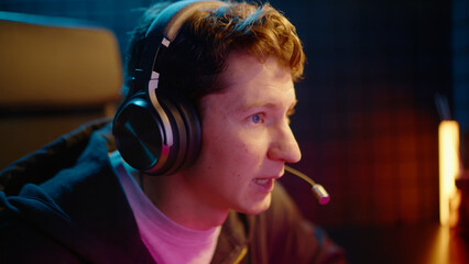 Young teen streamer gamer man playing online video game on computer. Esport concept gaming virtual entertainment. Cyber e sport videogame tournament live stream. Neon light. Tense player competition. © Татьяна Епанешникова
