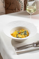 Creamy spinach pasta served in white bowl with rich sauce on minimal restaurant table