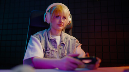 Young teen girl streamer gamer woman playing online video game on computer use joystick. Gaming console virtual entertainment. Cyber e sport videogame controller. Neon light. Tense player hold joypad. © Татьяна Епанешникова