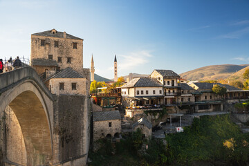 Fototapeta premium Historic stone arch bridge in mountain river valley during sunny morning side light. 