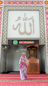 A Muslim girl walks carrying the Iqra Book in the mosque