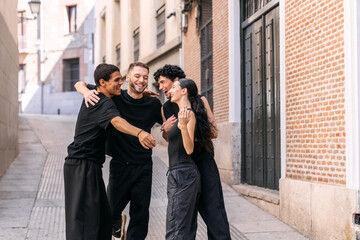 Happy young street dancers laughing and embracing in an urban alley. Group unity, friendship, and urban lifestyle