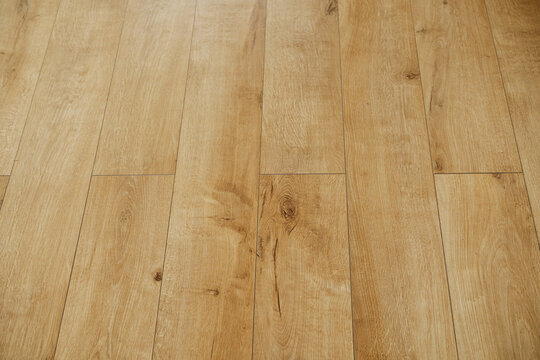 Close up of light brown wooden floor planks with subtle grain detail and slight perspective angle