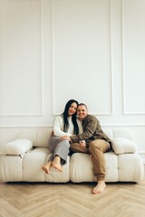 Obraz premium Couple sitting together on modern sofa in white living room