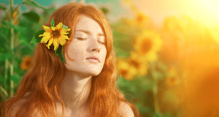 Redhead with freckles. Beautiful model in the sunset. Beauty girl. A woman wearing a flower crown stands in a field of yellow flowers illuminated by sunlight. © Miramiska