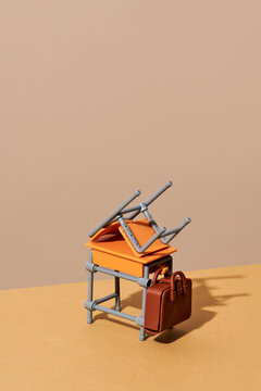 Stacked toy school furniture and briefcase in minimalist studio scene