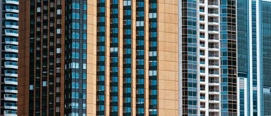 Tight telephoto view of tall city apartment and office towers, repeating vertical patterns of windows and balconies. © Alex