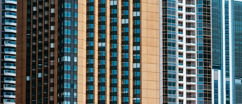 Tight telephoto view of tall city apartment and office towers, repeating vertical patterns of windows and balconies.