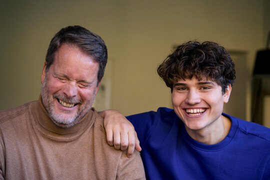 Father and son smiling together at home