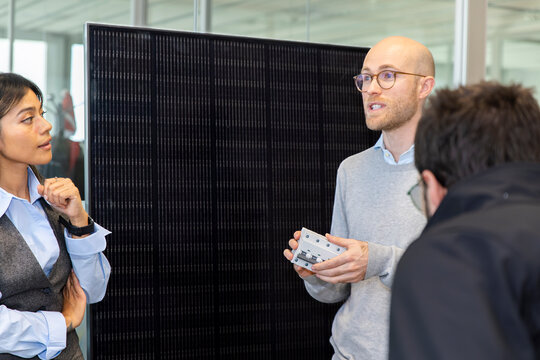 Employee presenting electrical component for solar installation in office