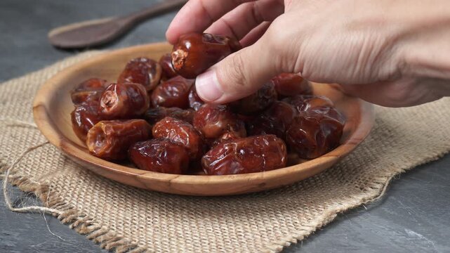 Footage of hand hlding dried dates in a wooden bowl