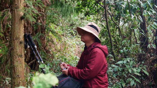 In the primeval forest, a man doing outdoor hiking is eating biscuits to replenish energy (close-up).