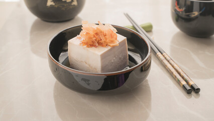 Tofu on a small plate with a portion of katsuobishi topping.