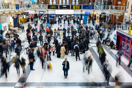 Mid adult woman standing in busy train station during rush hour