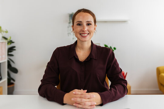 Businesswoman smiling at desk in office looking at camera