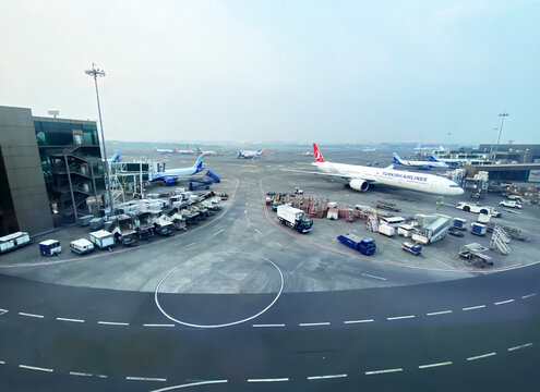 Istanbul, Turkey - October 20, 2025: Airplanes parked at an airport terminal with ground service vehicles and cargo containers visible on the tarmac in a busy aviation environment