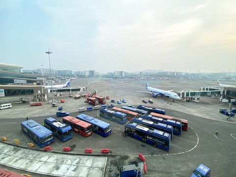 Mumbai, India - October 21, 2025: Mumbai International Airport view with parked buses, aircraft on tarmac, terminal building, and ground service vehicles visible in the background