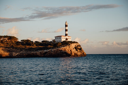 Far de Portocolom lighthouse on rocky cliff at sunset, Mallorca
