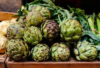 Fototapeta premium A vibrant display of fresh green artichokes and other healthy vegetables at a bustling market stall, showcasing natural produce ready for culinary use.
