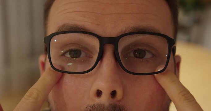 Close-up of a man adjusting and trying on new eyeglasses. Concept of vision correction, eye care, optician visit, eyewear fashion and personal style.