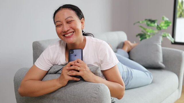 Happy Asian woman use mobile smartphone typing browsing say Wow yes found out great big win good news celebrate lottery jackpot