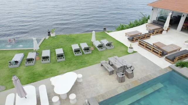 Luxury Villa with Infinity Pool Overlooking Waterfront, Elegant Outdoor Living Space - Aerial Drone Shot