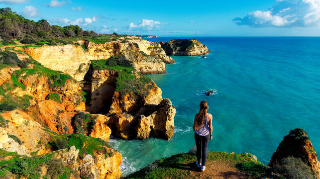 hapy woman enjoying the panoramic top view of rocky beaches with cliffs, Algarve in Portugal