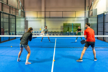 People playing pickleball doubles match on indoor court © unai