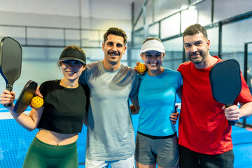 Pickleball players team smiling holding paddles and ball on court © unai