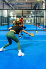Woman playing pickleball on indoor court hitting ball