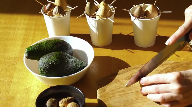 Close-up of woman cutting the base of an avocado pit in natural sunlight during preparation for sprouting. Represents circular food practice, home based regeneration habit, and waste reduction mindset