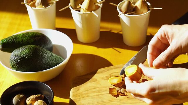 Step by step footage of wooden sticks inserted symmetrically into avocado seed to create sprouting support structure. Represents home gardening experiment, urban farming, and food waste reuse trend.