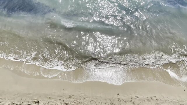 Mar, ola y arena de playa desde arriba con orilla y marea de espuma a vista de dron en vacaciones de verano