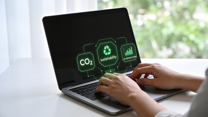 Person typing on laptop with sustainability graphics