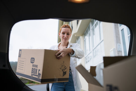 Person loading moving box from car during relocation in front of home