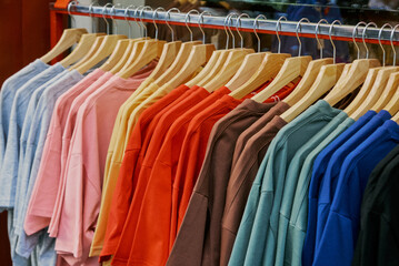 Obraz premium Colorful T-Shirts on Wooden Hangers in Clothing Store
