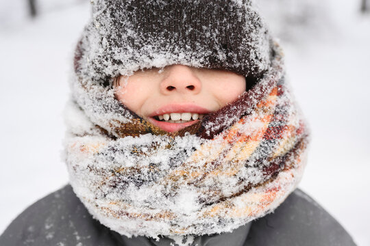 Smiling child bundled in scarf and hat outdoors in snowy winter