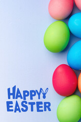 Fototapeta premium Colorful eggs and happy easter greeting on a light blue background in spring season
