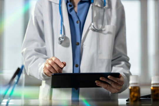 Doctor using tablet computer with stethoscope in clinic office