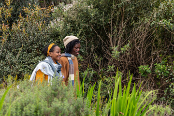 African American couple walking through garden wearing mustard sweater yellow headband beige beanie