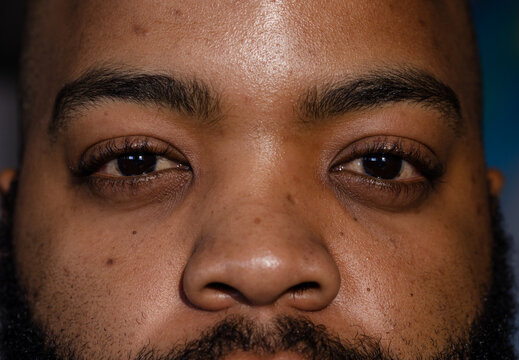 African American man looking directly into camera in studio, showing pores, stubble, eyebrows