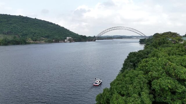 panoramic drone view of the Adomi Bridge over the Volta River in Akosombo, Ghana. Showcases the vast river landscape, lush tropical vegetation, and infrastructure
