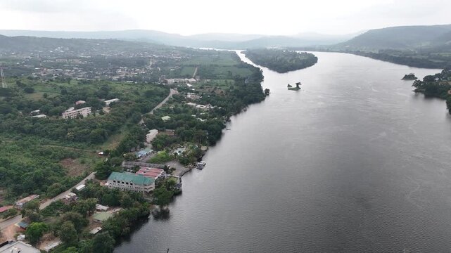Cinematic aerial drone panorama of the Akosombo Dam and the expansive Volta River in Ghana. High-angle view of West African infrastructure and lush natural scenery
