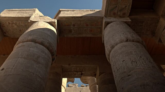 The structural intersection of vertical columns and horizontal lintels within the Karnak Temple complex. The shots emphasize the monolithic sandstone architraves that span the gaps between pillars.