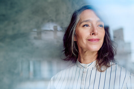 Confident businesswoman smiling, looking away from camera, reflecting on plans, and envisioning success through business growth